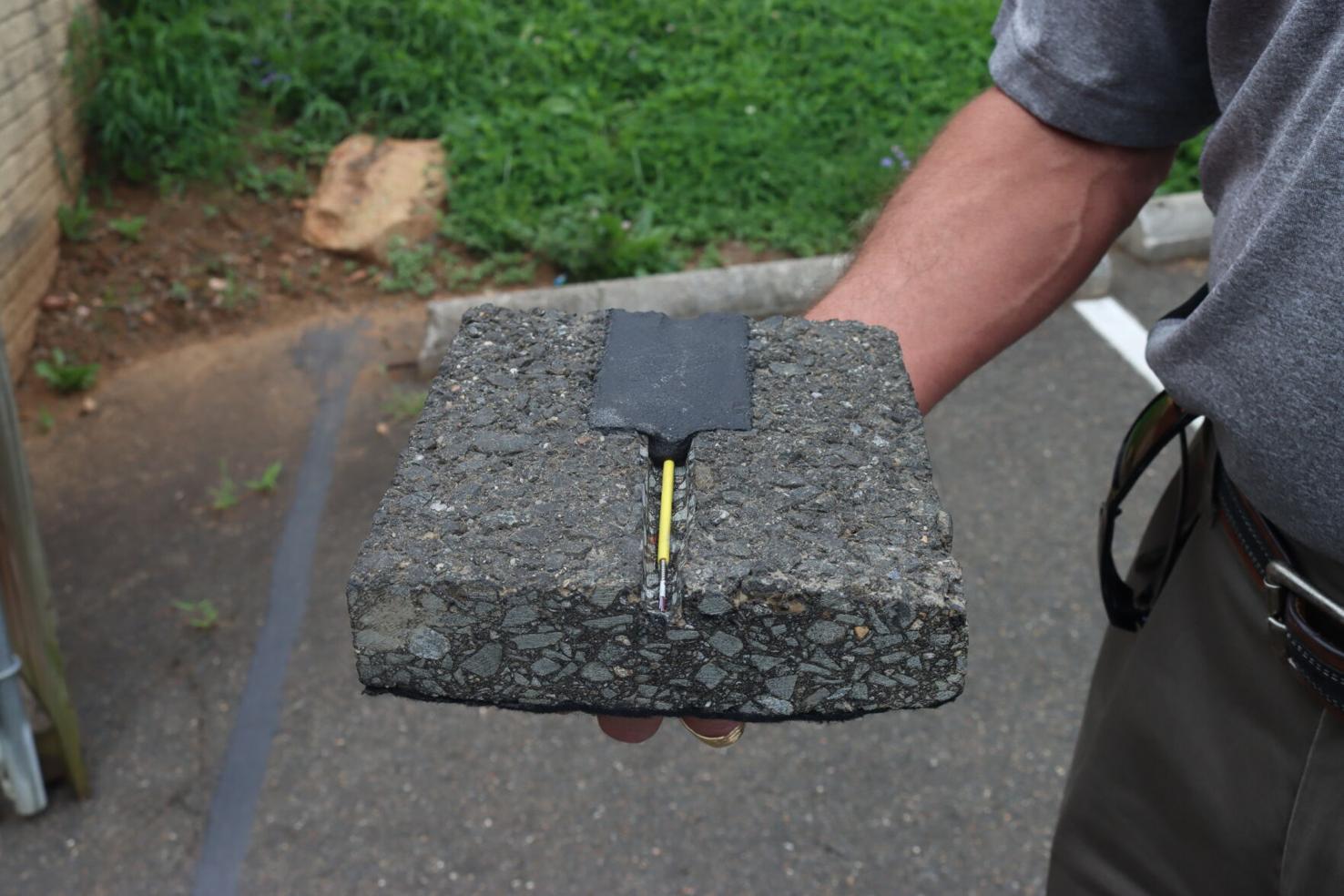 Keith Turner, TRAXyL vice president of sales, holds a cross-section of a fiber cable embedded in the pavement.